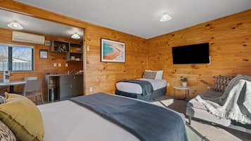 Ein gemütliches Blockhauszimmer mit Bett, Sofa, Schreibtisch und Fernseher.