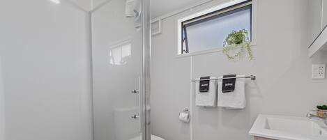 Een moderne badkamer met een douchecabine van glas, een toilet en een wastafel met houten opbergruimte.