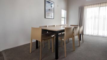 A dining area with a rectangular table and six chairs, a framed picture on the wall, and a window with blinds.