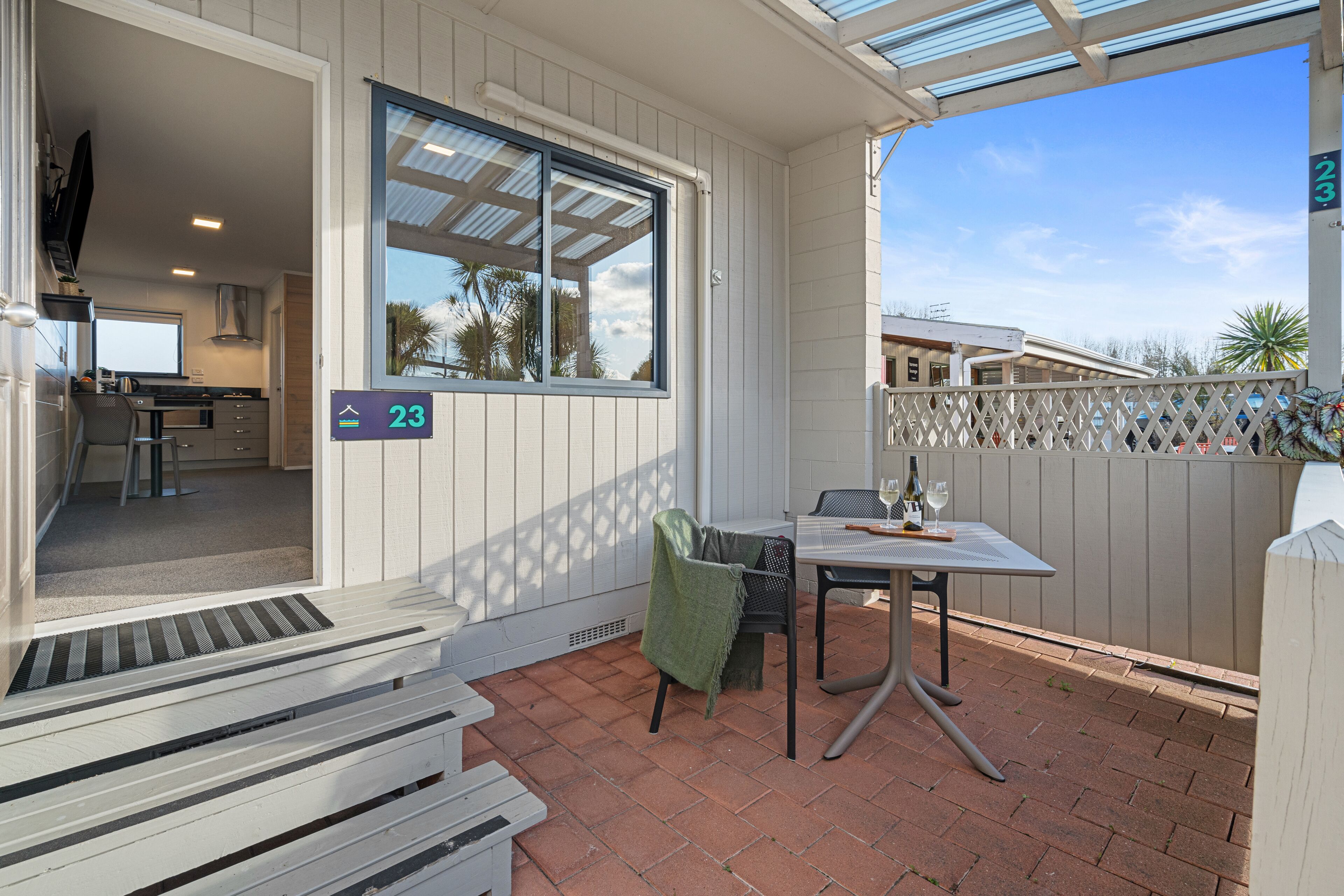A patio with a table and chairs, a window, and a door leading to a kitchen.