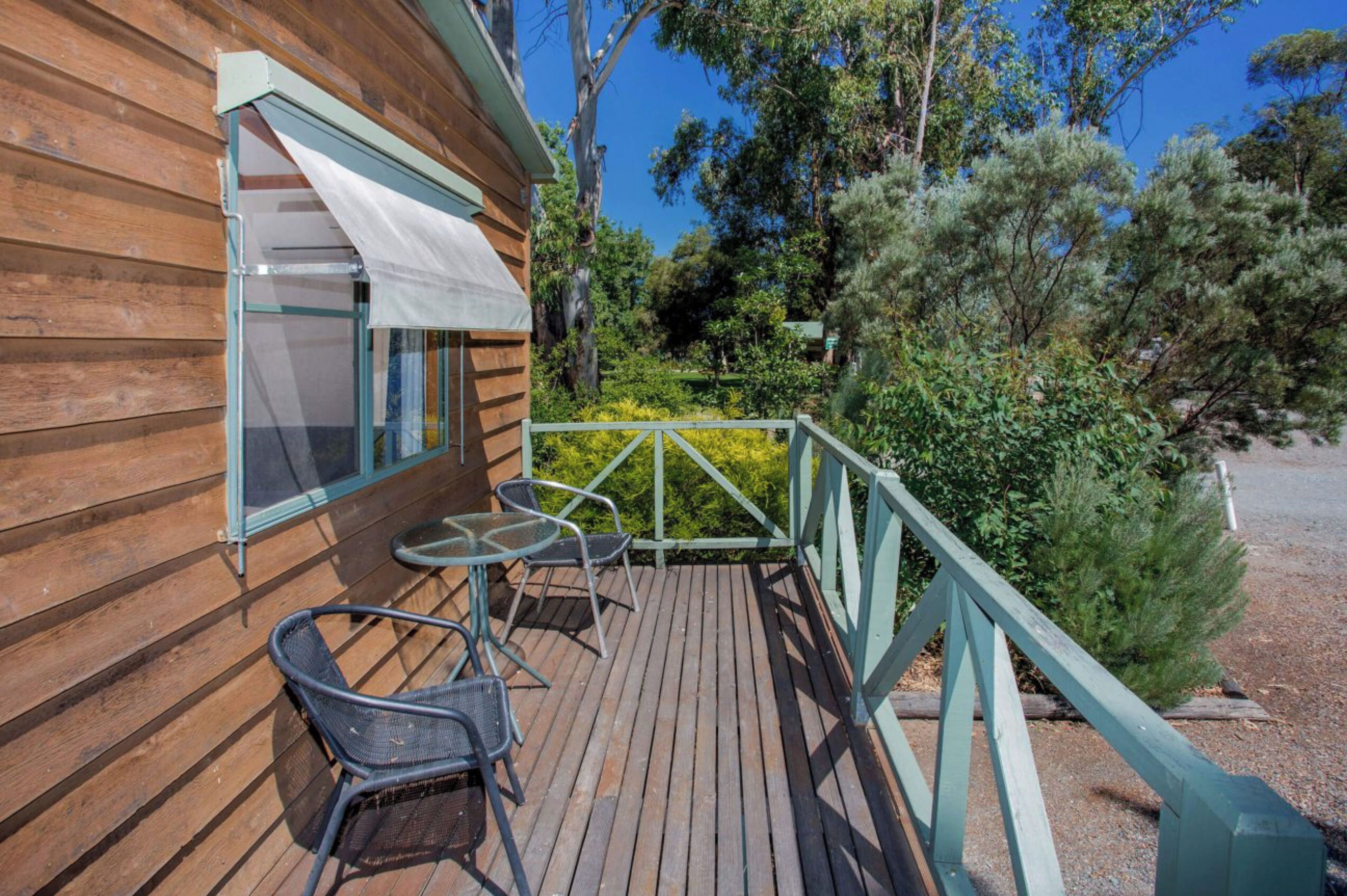 A wooden cabin with a balcony, a table, and two chairs.
