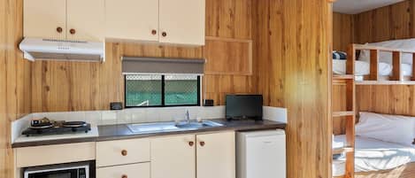 A compact kitchen with a microwave, stove, sink, and dishwasher.
