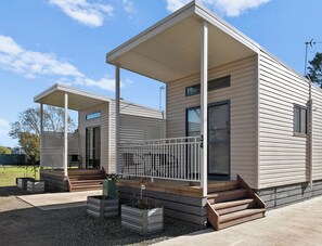 A modern, two-story mobile home with a covered porch and a small deck area. - Shepparton Holiday Park (Orrvale)