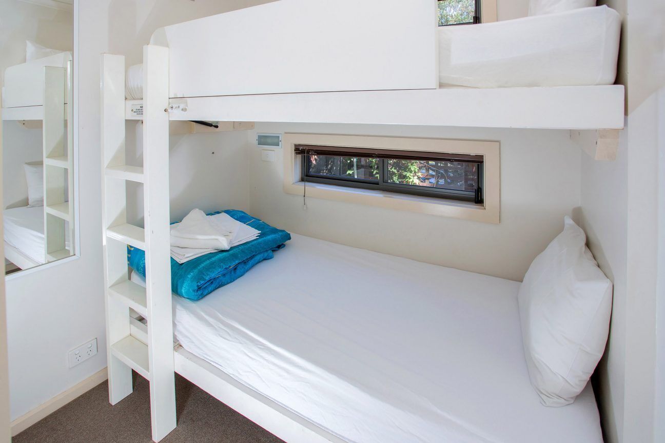 Un lit superposé avec une fenêtre, un bureau et une étagère.