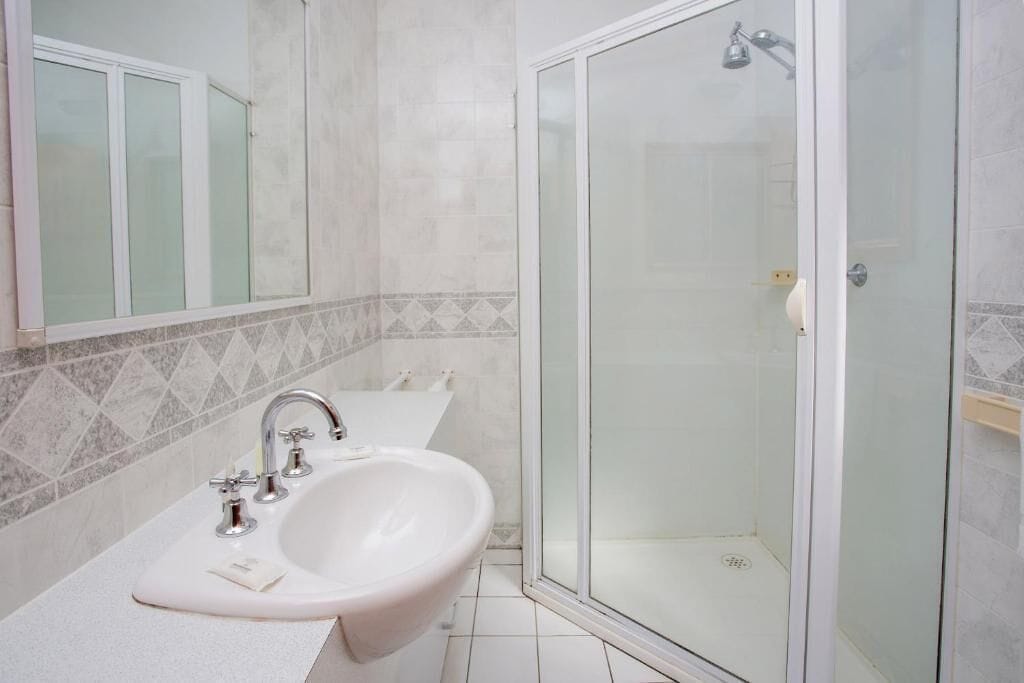 Ein Badezimmer mit Waschbecken, Spiegel und einer Duschkabine.