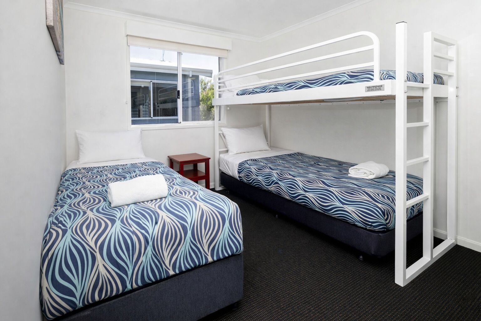 A room with two bunk beds, a small table, and a window.