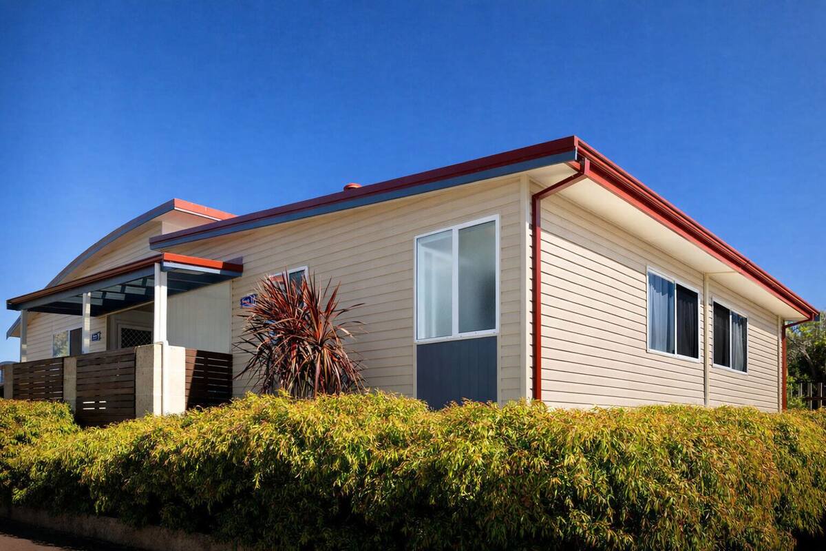 Ein Bungalow mit überdachter Veranda, Garage und kleinem Garten.