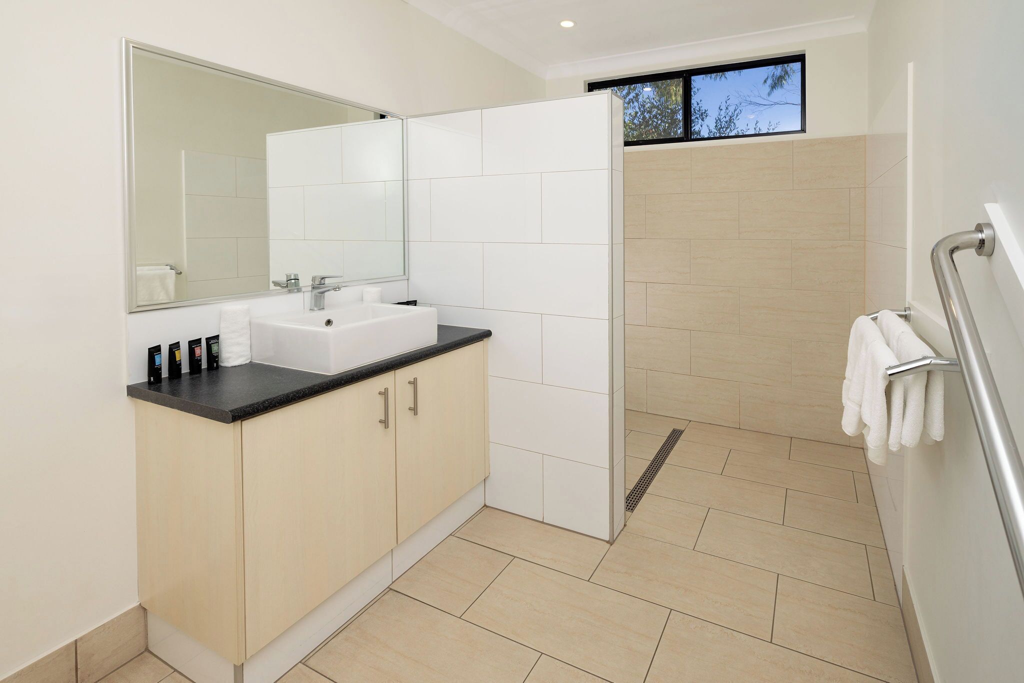 A modern bathroom with a sink, mirror, and shower area.