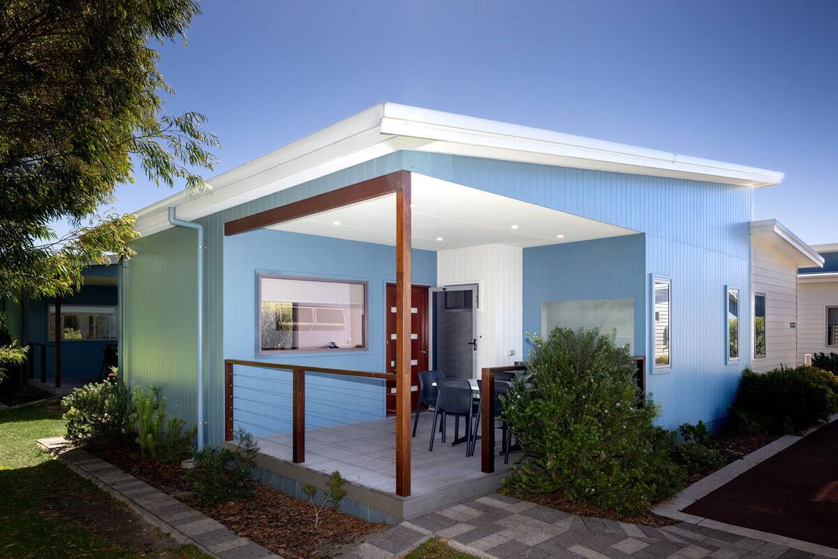 Ein modernes Haus mit einer überdachten Terrasse, einem Essbereich und einer Tür zum Innenraum.