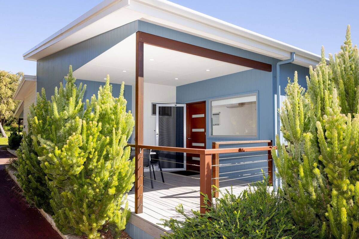 Ein modernes Haus mit überdachter Veranda, einer Tür und einem Fenster.
