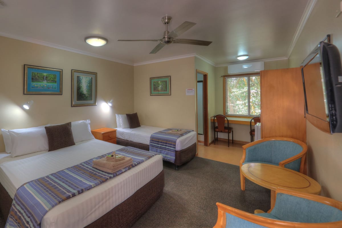 Una habitación de hotel con dos camas, un escritorio, una silla y un televisor.