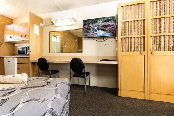 A room with a bed, a desk, two chairs, a television, and a wardrobe.