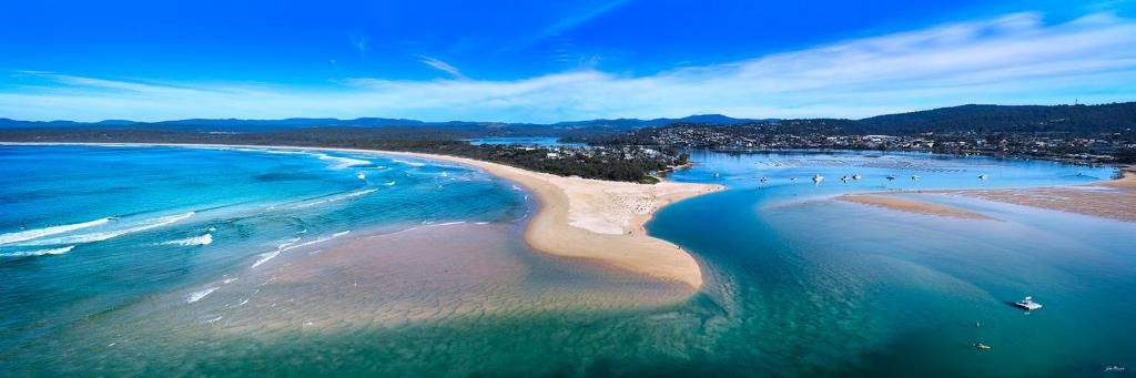 Vista aérea de una zona costera con aguas cristalinas, una playa arenosa y un pequeño poblado.