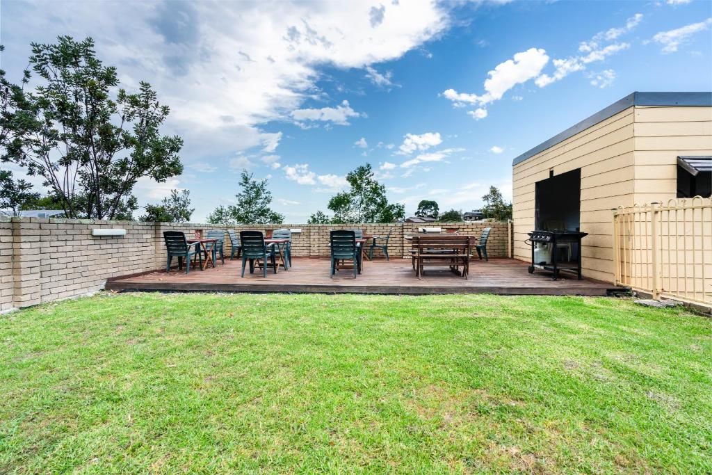 An outdoor patio area with a brick wall, a grill, and a seating arrangement.