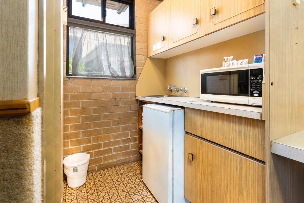 A compact kitchen with a refrigerator, microwave, and wooden cabinets.