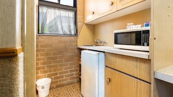 Cozinha compacta com geladeira, micro-ondas e armários de madeira.