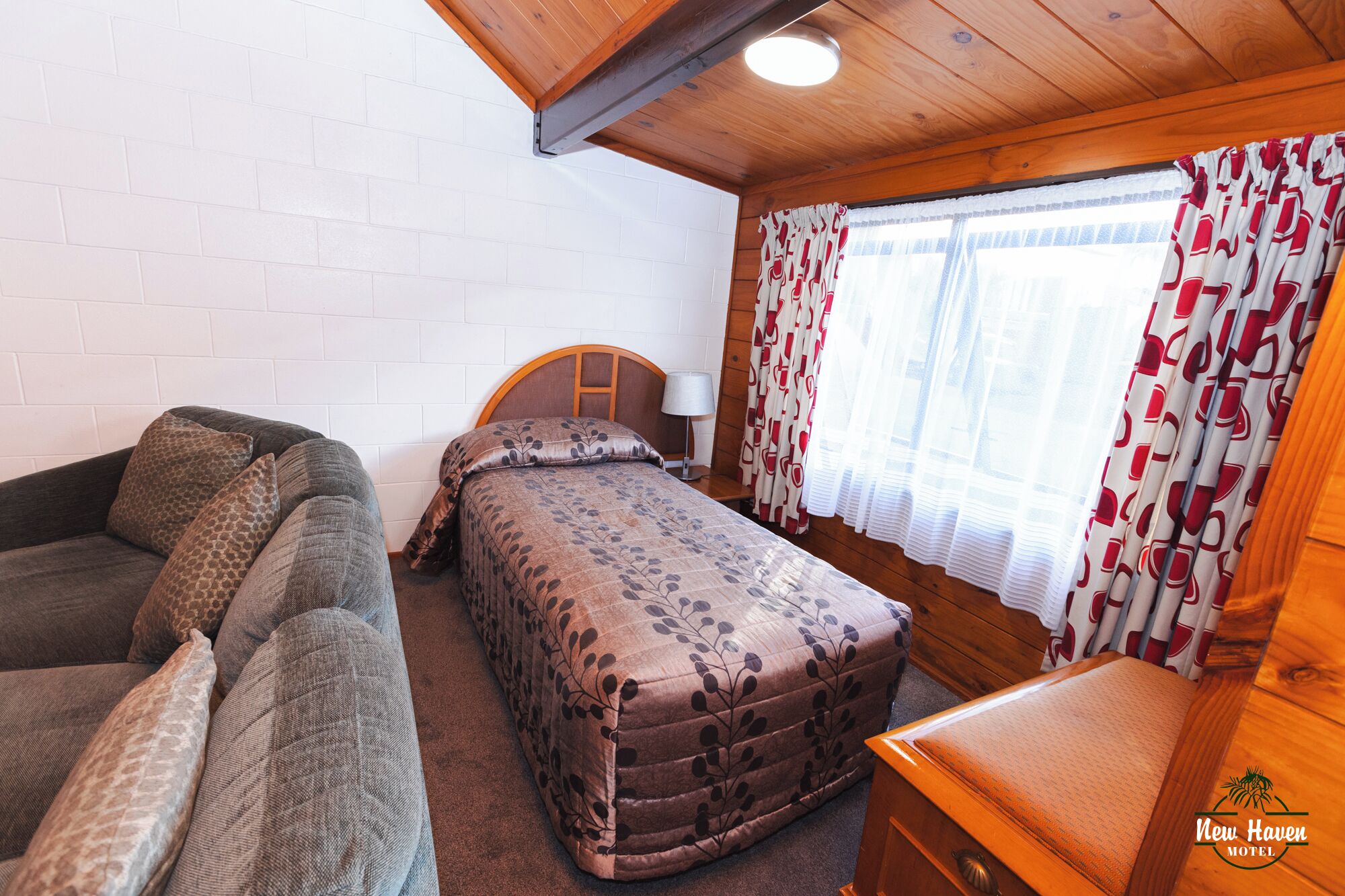 A cozy room with a bed, a sofa, and a wooden headboard.