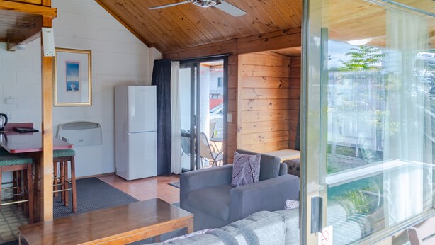 A cozy room with a sofa, wooden table, and a refrigerator.