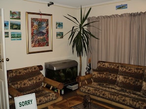 Ein Wohnzimmer mit einer Couch, einem Fernseher und einem Schild mit der Aufschrift 'Sorry'.