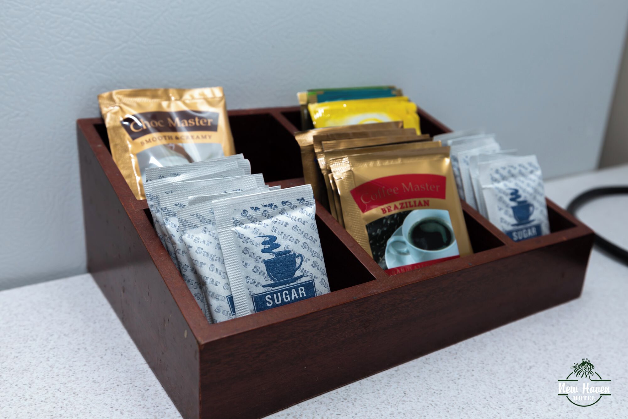 Une boîte en bois contenant divers sachets de café et de sucre.
