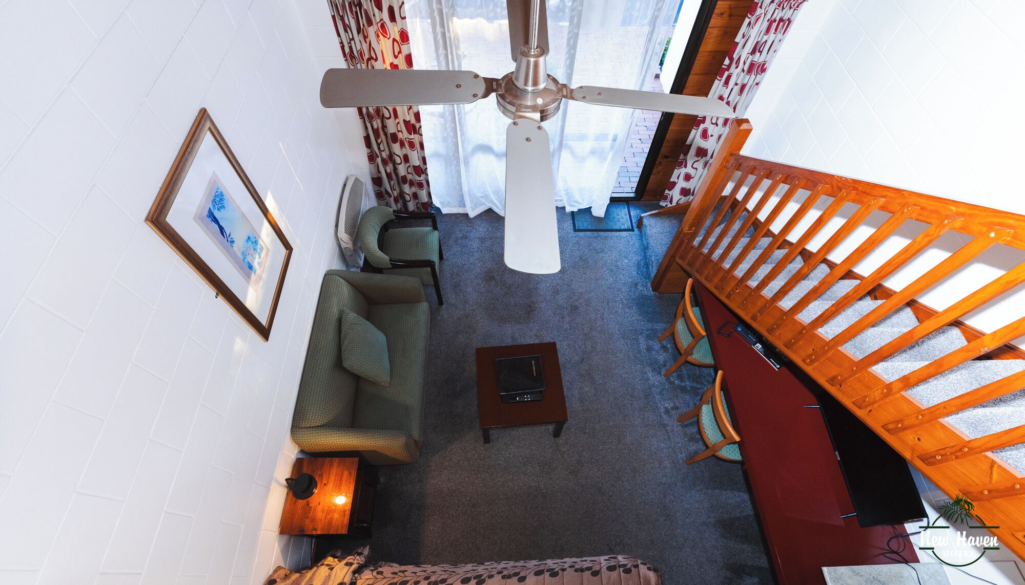 Una sala de estar con ventilador de techo, un sofá, una mesa de centro y una escalera.