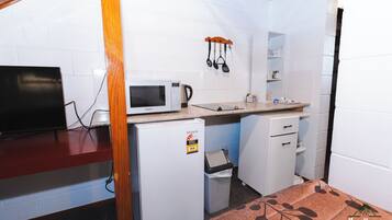Una kitchenette compacta con microondas, un refrigerador pequeño y un lavamanos.