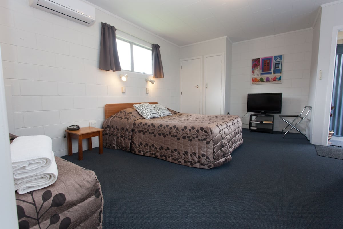 A hotel room with a bed, a TV, a desk, and a chair.