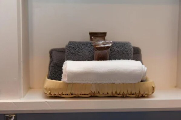 A bathroom with a white sink, a towel, and a wooden brush.