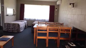A room with a bed, a desk, a chair, and a table.