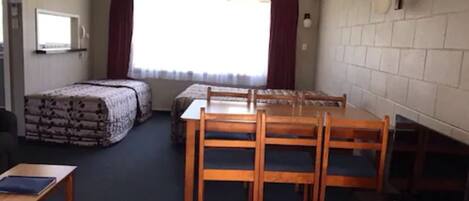 A room with a bed, a desk, a chair, and a table.