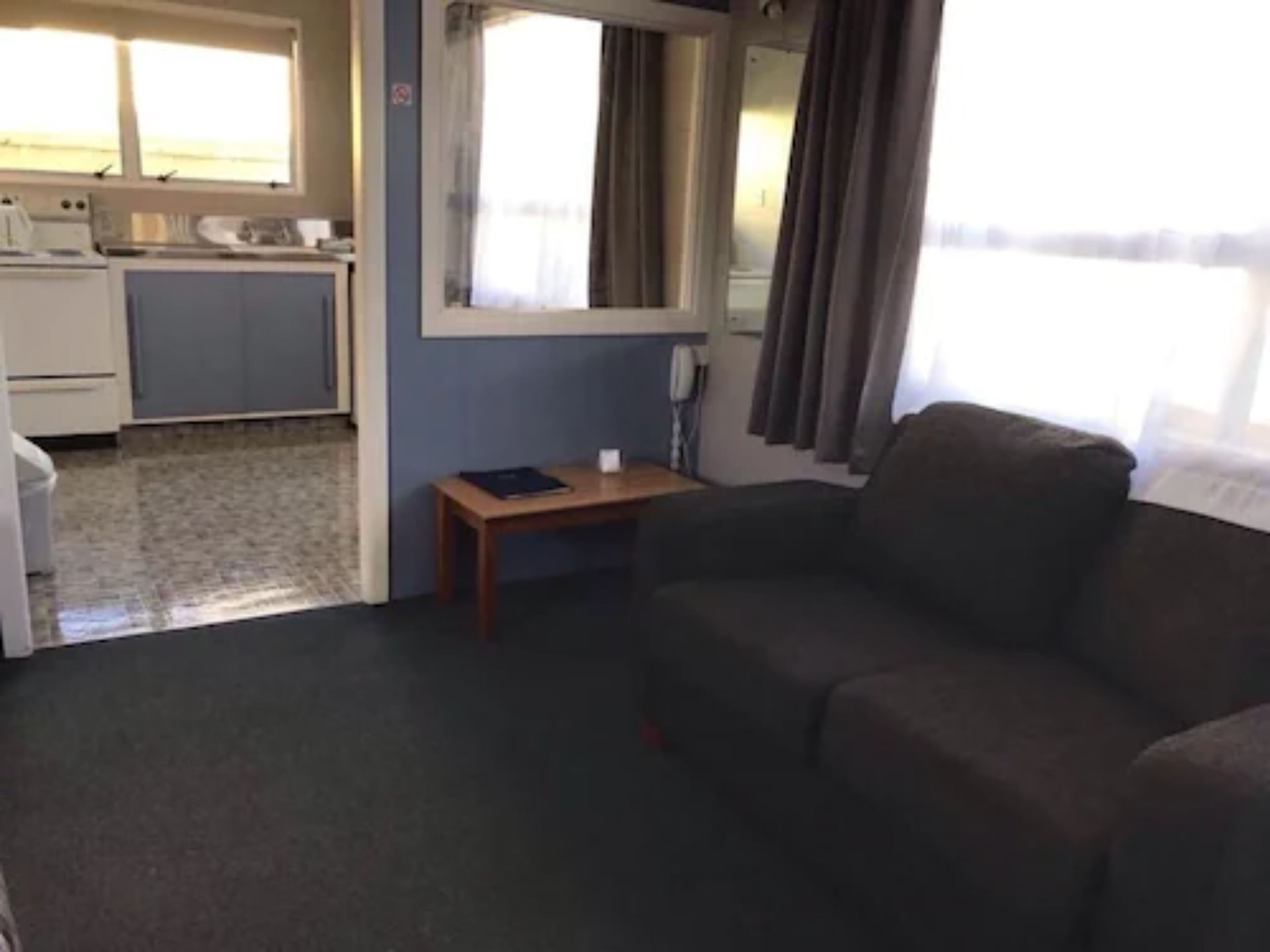 A compact living space with a kitchenette, a sofa, and a small table.