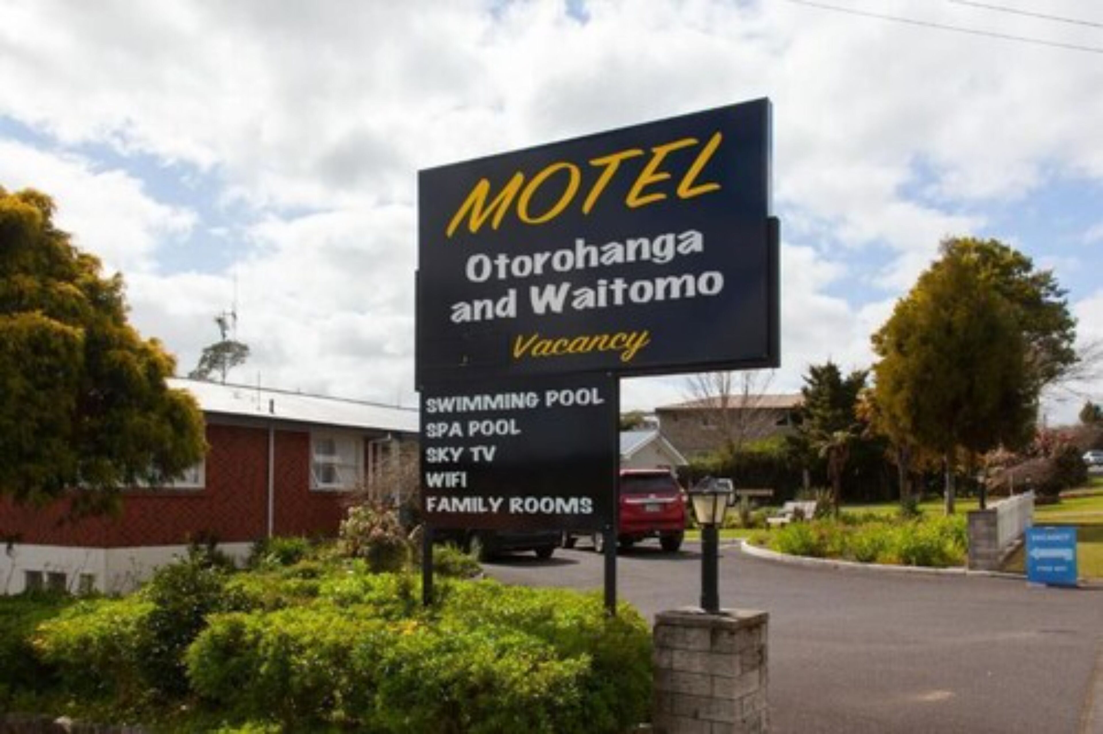 Letrero de motel con servicios que incluyen piscina, jacuzzi, Sky TV, WiFi y habitaciones familiares.