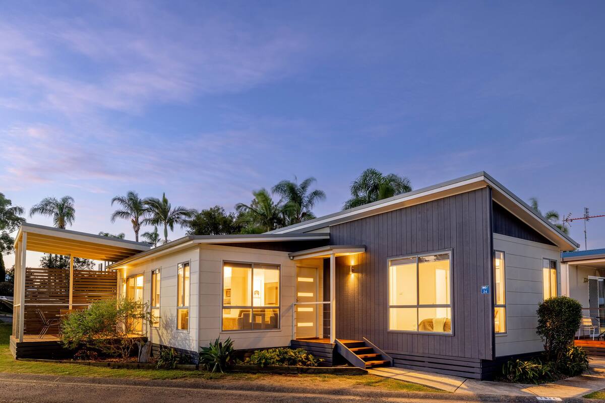 A modern house with large windows, a covered porch, and a staircase leading to the entrance.