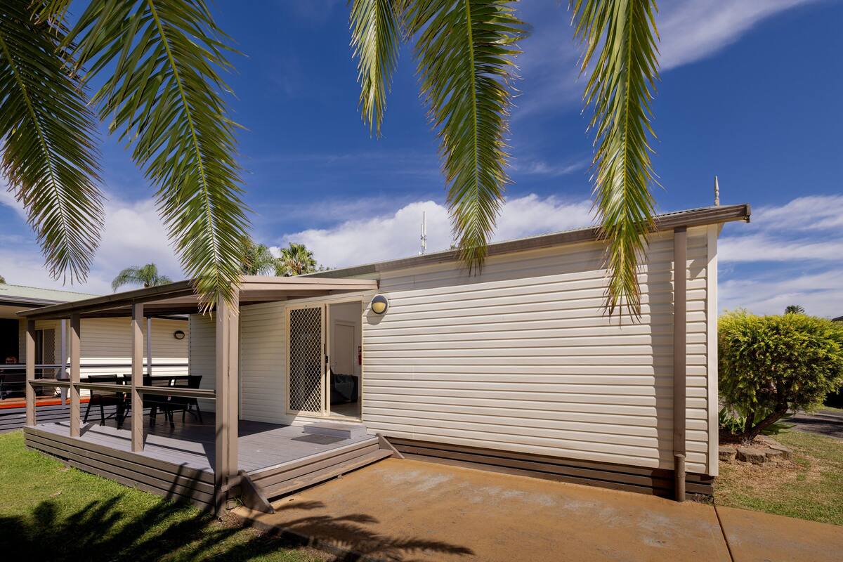 A single-story mobile home with a patio area, a covered outdoor seating area, and a small garden.