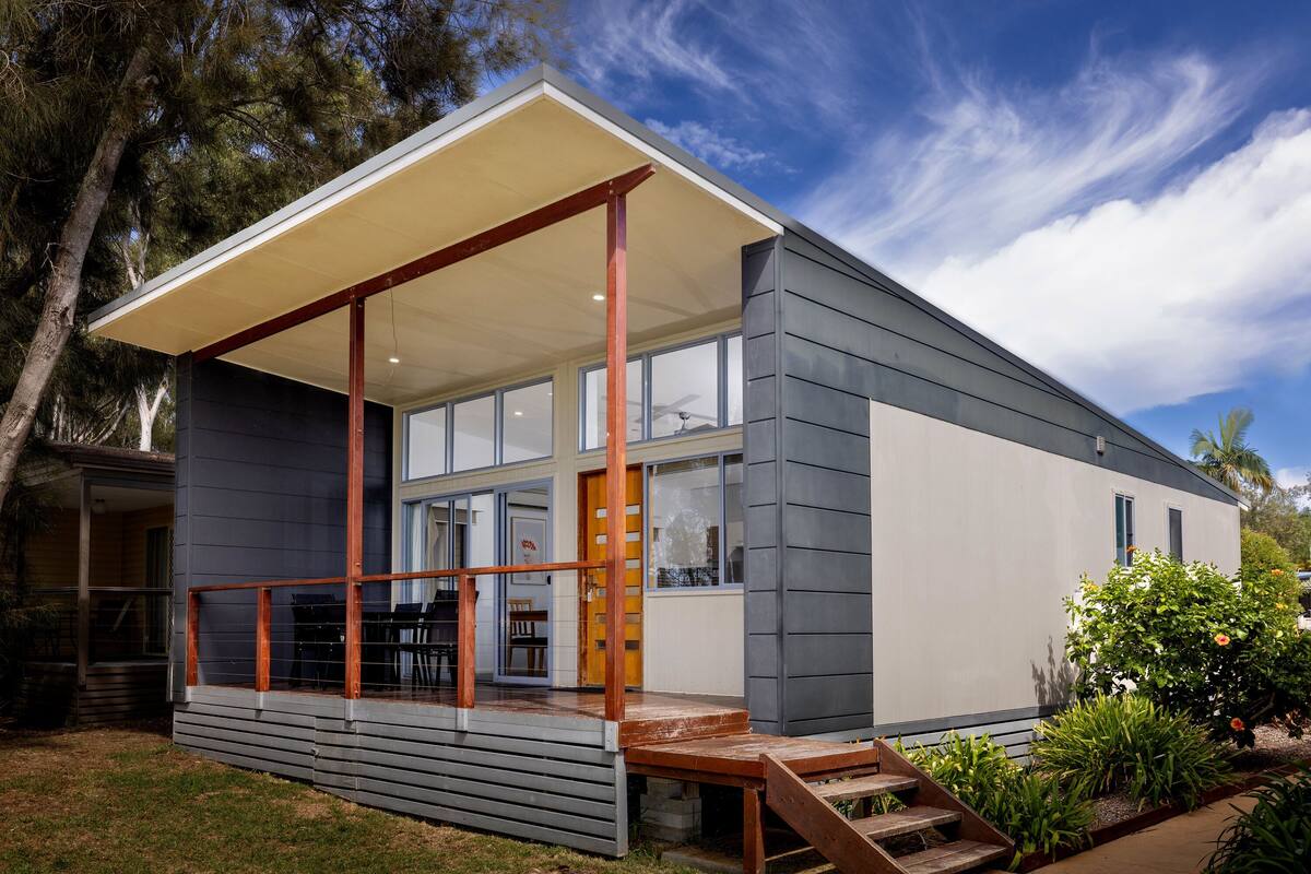 A modern house with a covered porch, large windows, and a staircase leading to the entrance.
