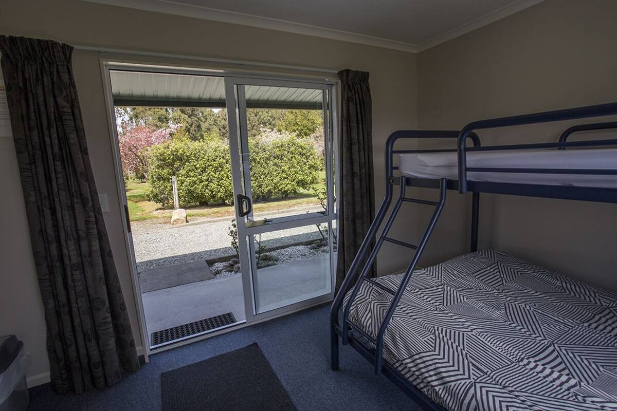 A room with a bunk bed, a sliding glass door leading to an outdoor area, and a small rug on the floor.