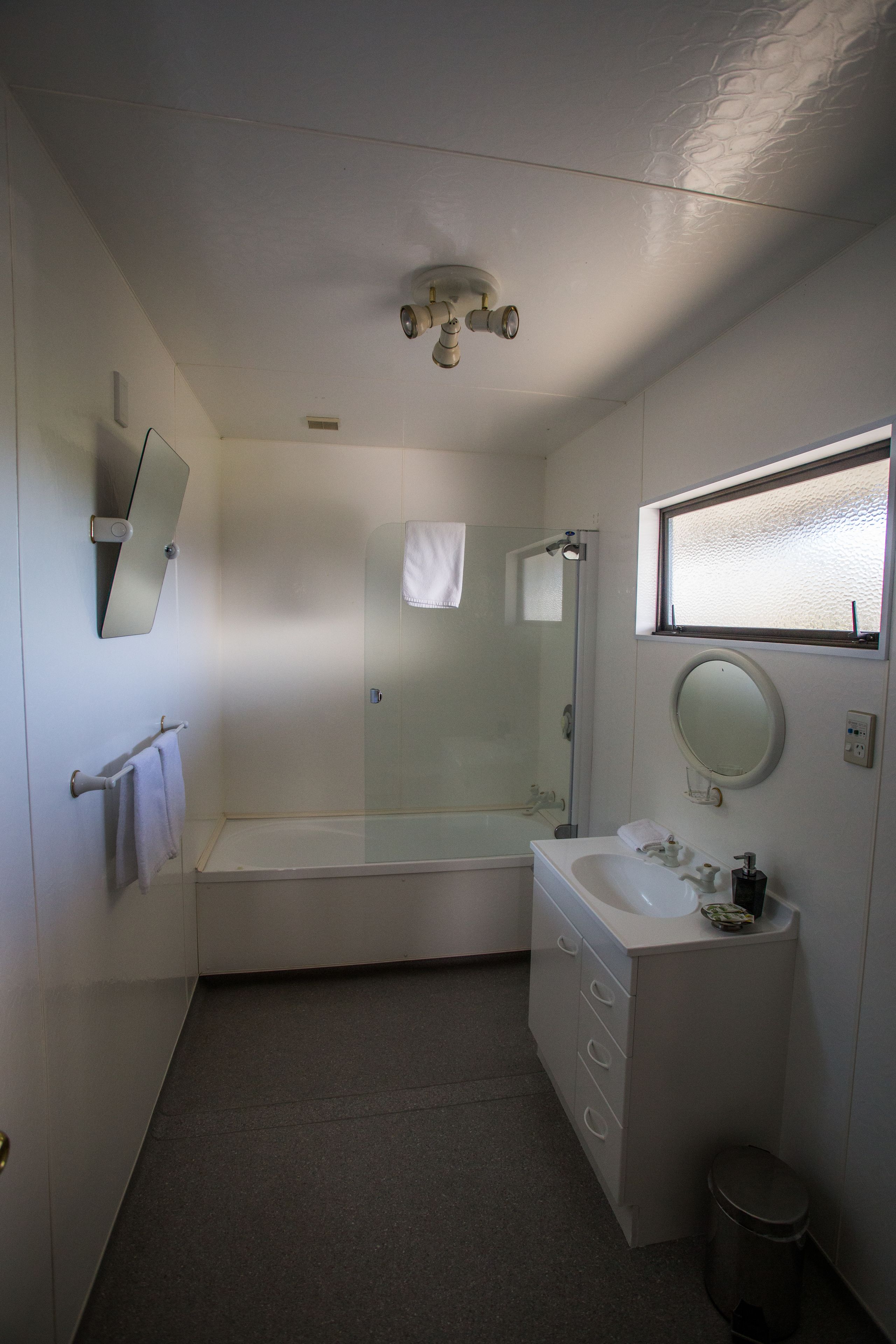 A bathroom with a bathtub, a sink, a mirror, and a window.