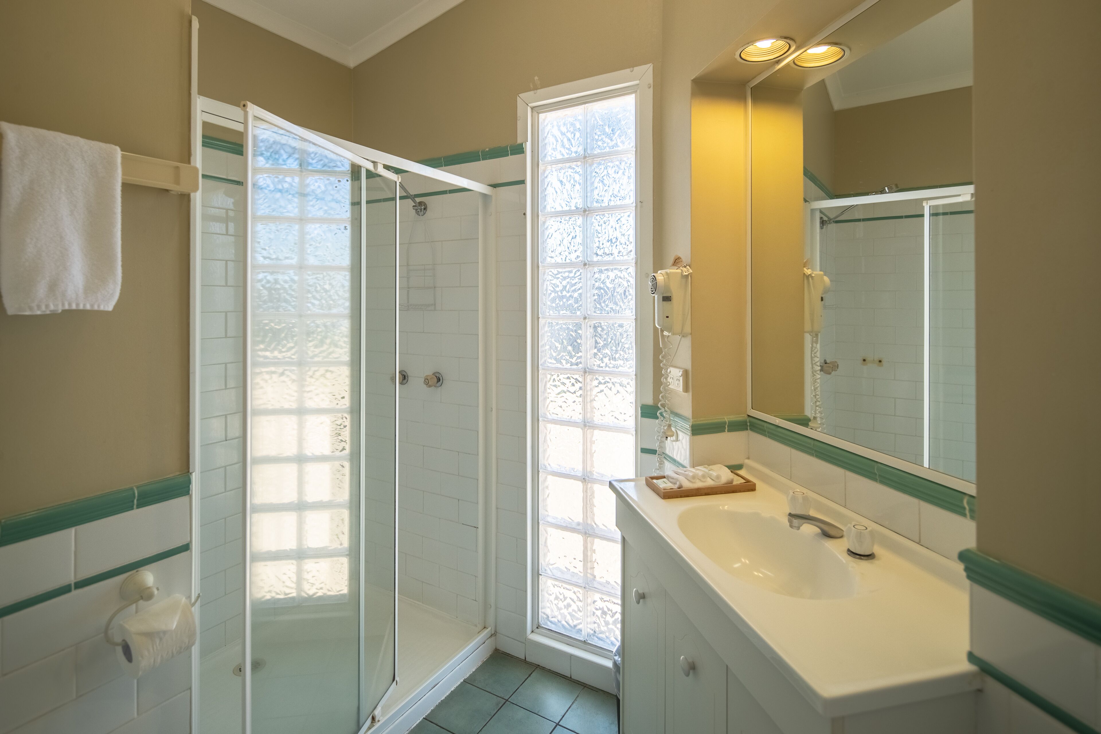 A bathroom with a glass shower enclosure, a sink with a mirror, and a towel rack.