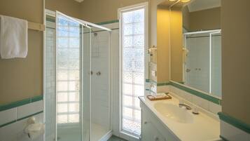 A bathroom with a glass shower enclosure, a sink with a mirror, and a towel rack.
