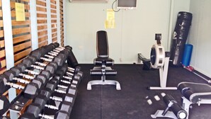 Une salle de sport avec plusieurs rangées de haltères, un vélo d’appartement et un sac de frappe.