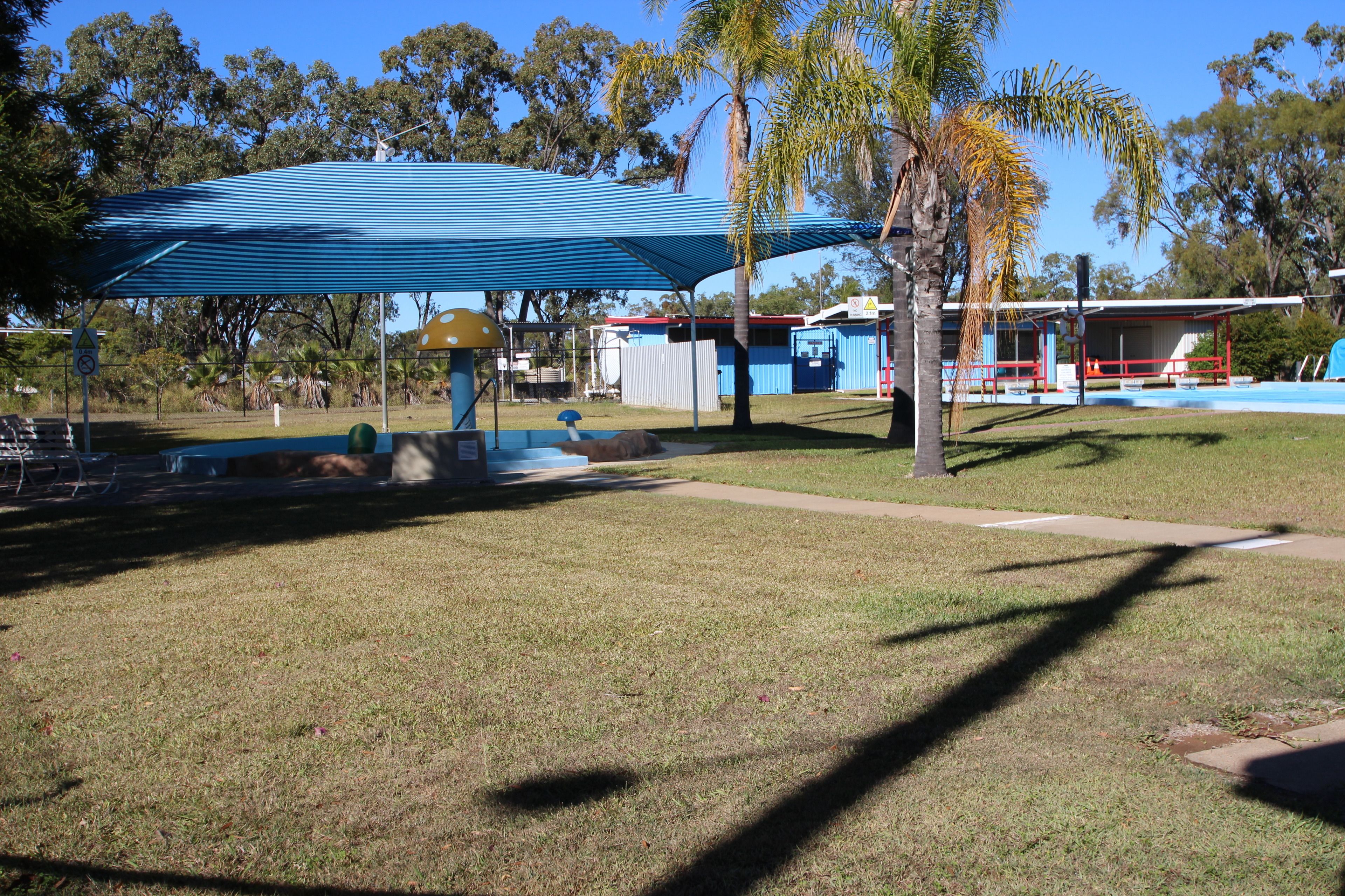 A park with a blue-roofed pavilion, a playground, and a swimming pool.