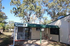 Un petit immeuble de bureaux avec un auvent vert, un vélo garé devant et une enseigne indiquant « BUREAU ».