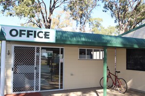 Un petit bâtiment avec une enseigne indiquant « BUREAU » et un vélo garé à l’extérieur.