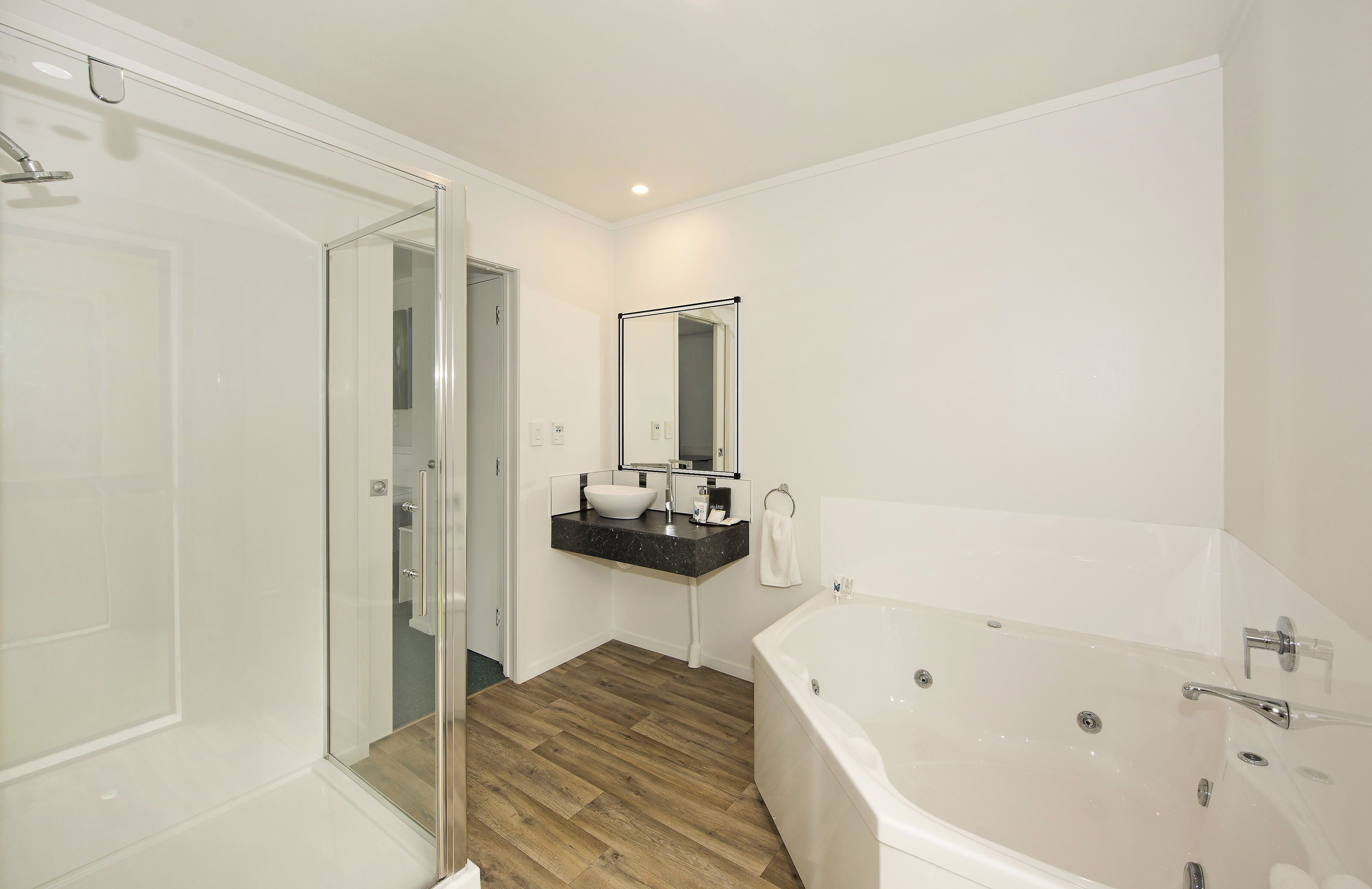 Un baño moderno con cabina de ducha de vidrio, una bañera independiente y un tocador con espejo.