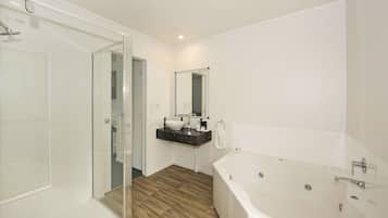 Un baño moderno con cabina de ducha de vidrio, una bañera independiente y un tocador con espejo.