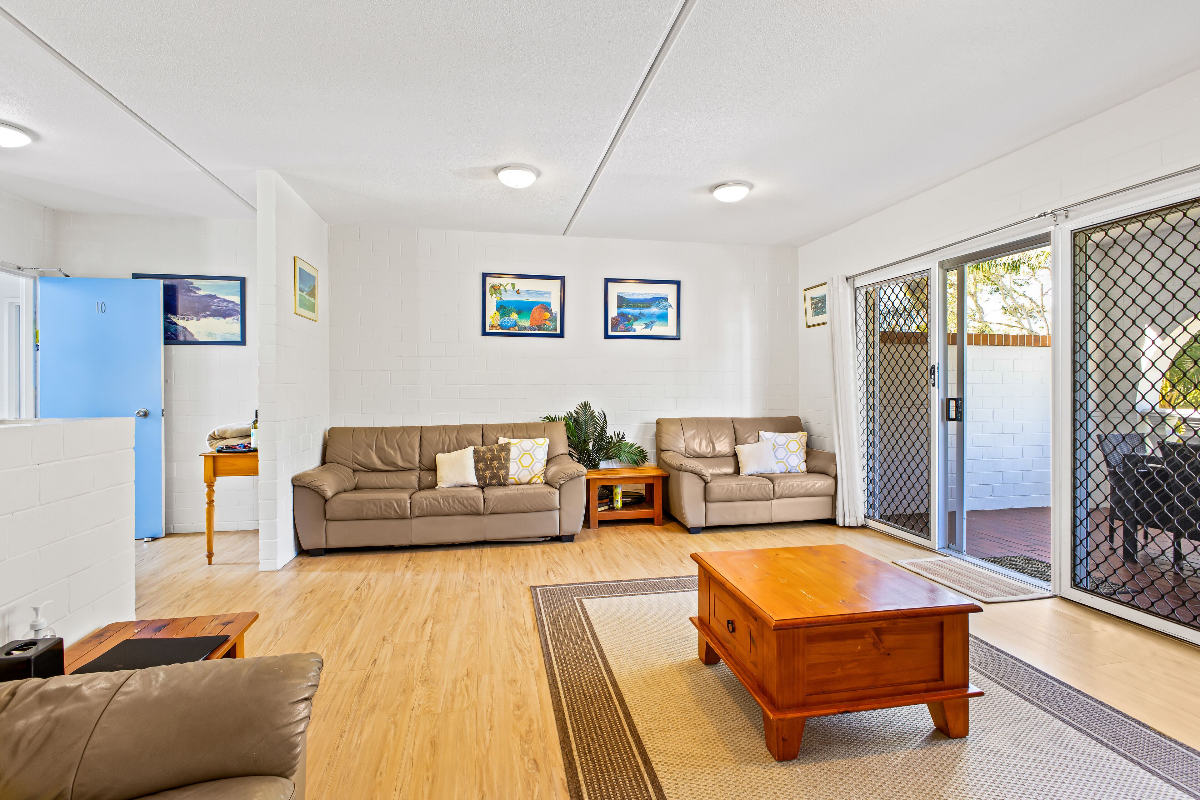 A spacious living room with two sofas, a wooden coffee table, and a sliding glass door leading to an outdoor area.