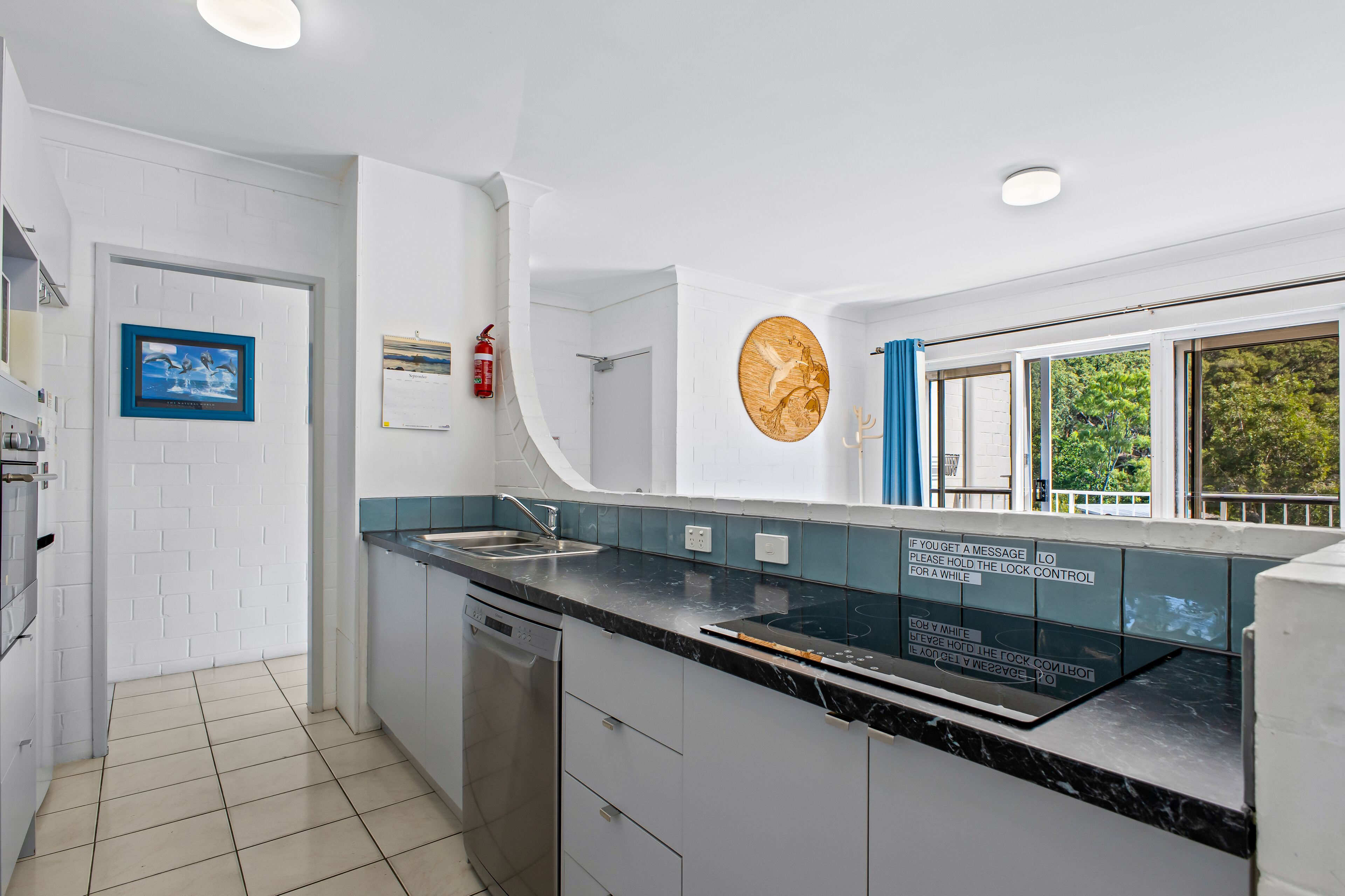 A modern kitchen with white cabinetry, a black countertop, and a built-in dishwasher.