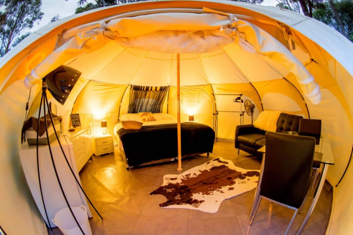A tent with a bed, a chair, a table, and a cowhide rug.
