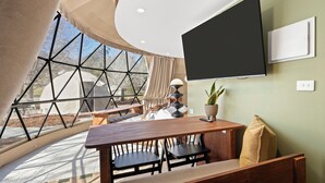 Un comedor con un amplio ventanal, un televisor de pantalla plana y una mesa de madera.