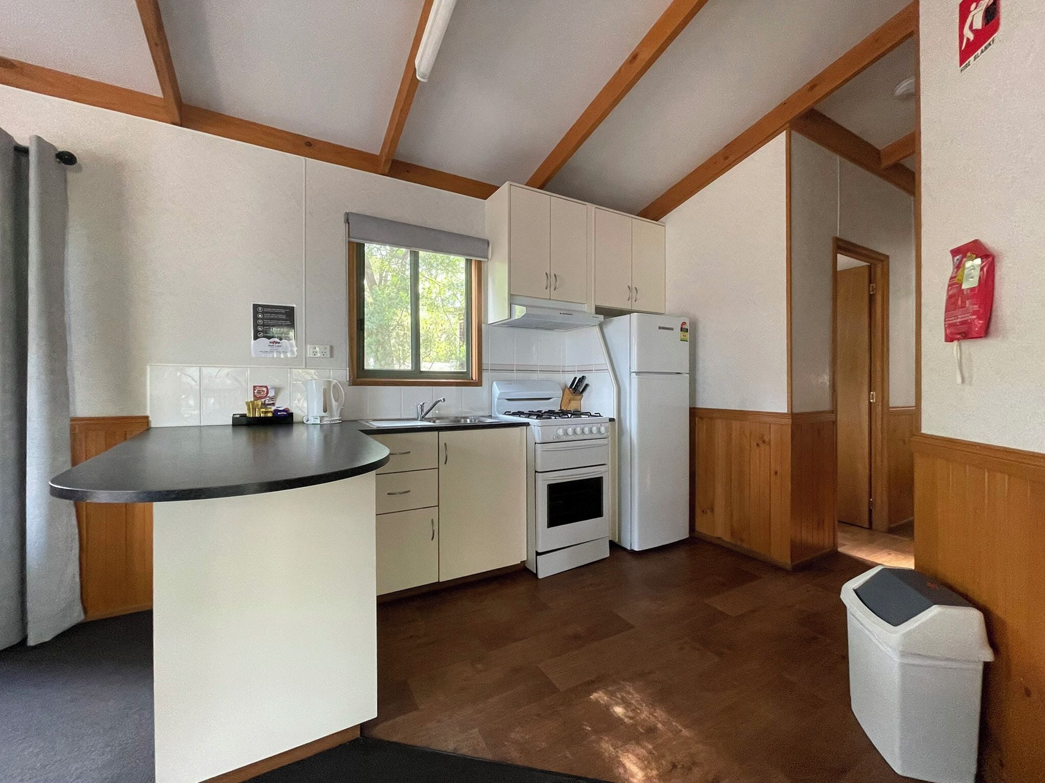 Una cocina compacta con armarios blancos, estufa integrada y refrigerador.